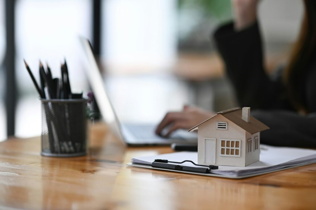 House model and clipboard on wooden table. Mortgage and real estate investment.